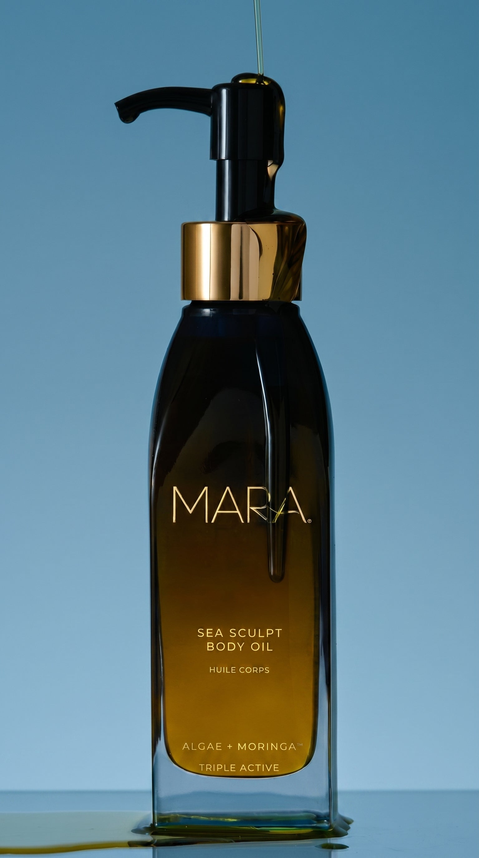 Bottle of sea sculpt body oil with oil dripping down