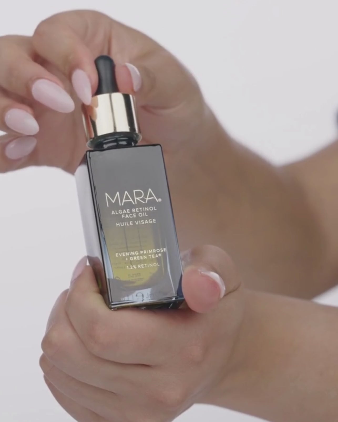 Hand squeezing algae retinol oil into its bottle 